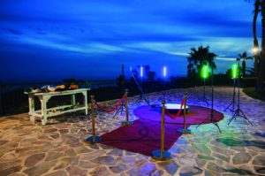 Outdoor beach wedding ceremony setup with colorful lighting at sunset, perfect for romantic beachfront weddings.