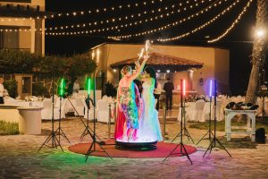 Elegant wedding reception with bride and guests dancing on a rotating dance floor at night.