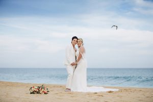 Elegant wedding couple on the beach with ocean backdrop, perfect for seaside wedding photography and wedding planning.