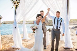 Beautiful beach wedding ceremony with bride and groom celebrating at EMweddings.