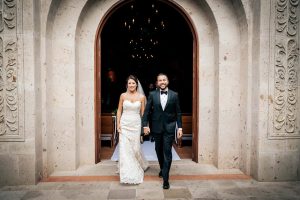 Elegant wedding couple exiting church, bride and groom hand in hand, celebrating marriage at EMweddings.
